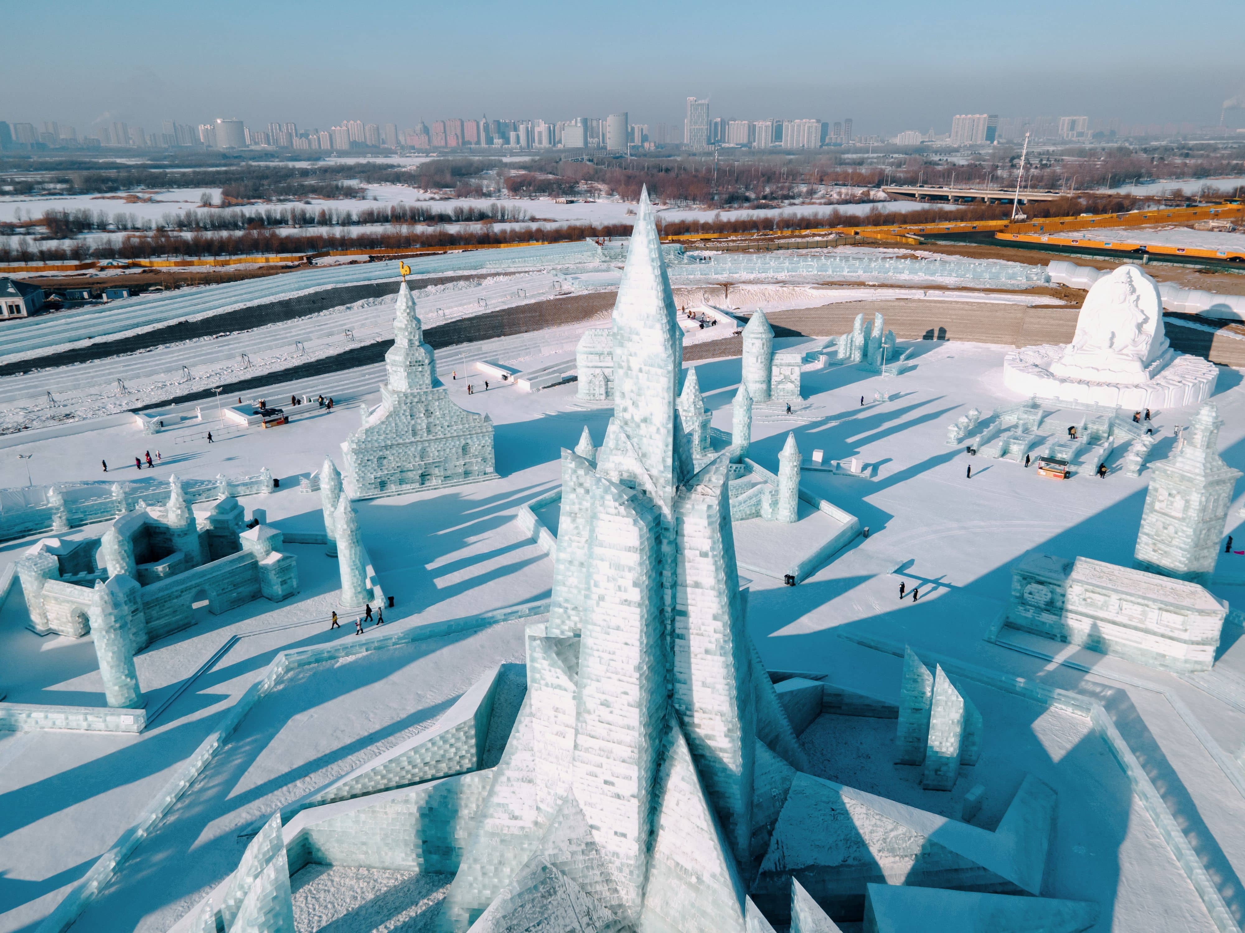 Workers cutting ice blocks from the frozen Songhua River with saws and dragging them onto the bank during the December ice harvest for Harbin Ice and Snow World