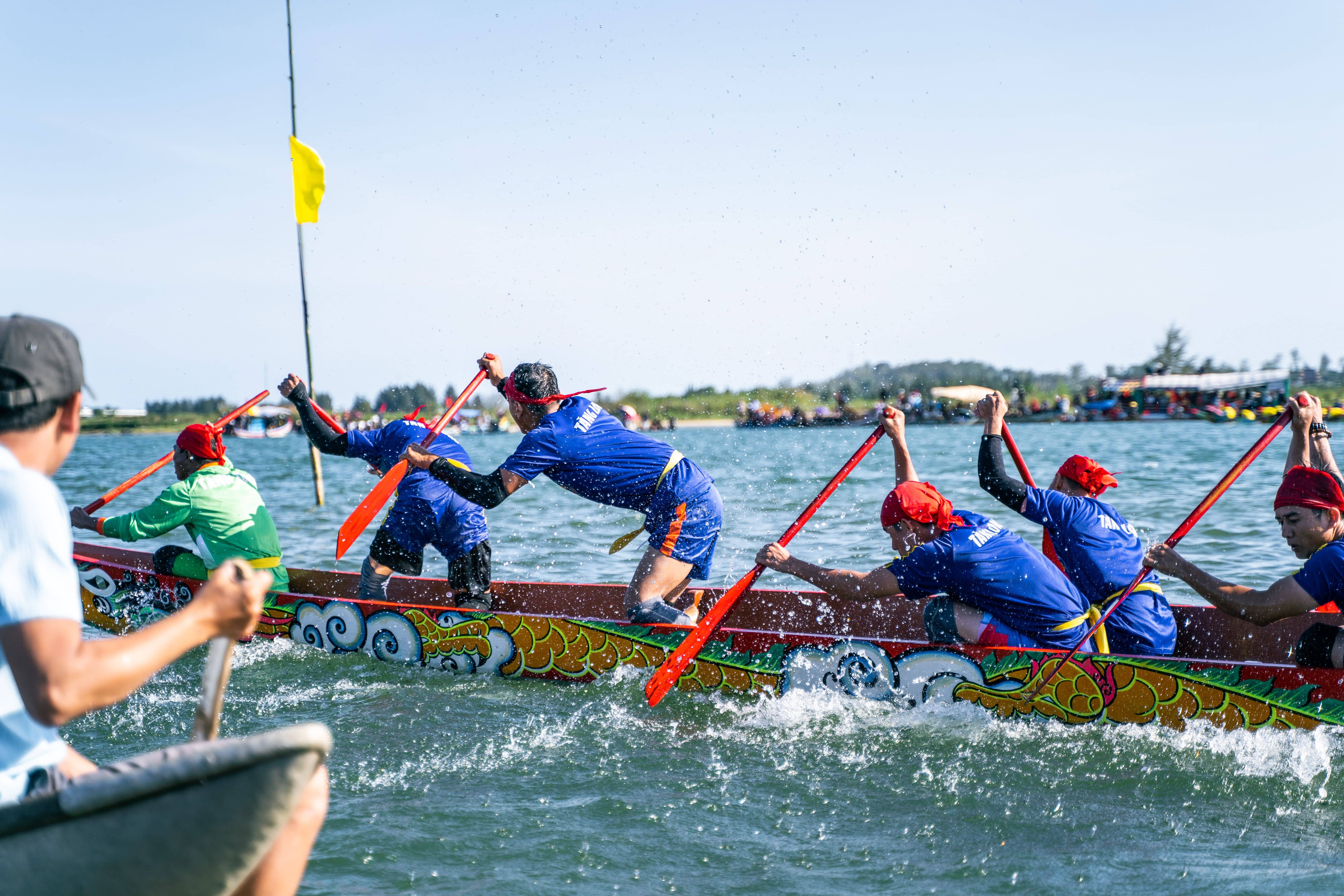 A long dragon boat with around 30 paddlers leaning hard into a tight bend during the Diejiao dragon boat drifting race in Foshan, water spraying up at the corner