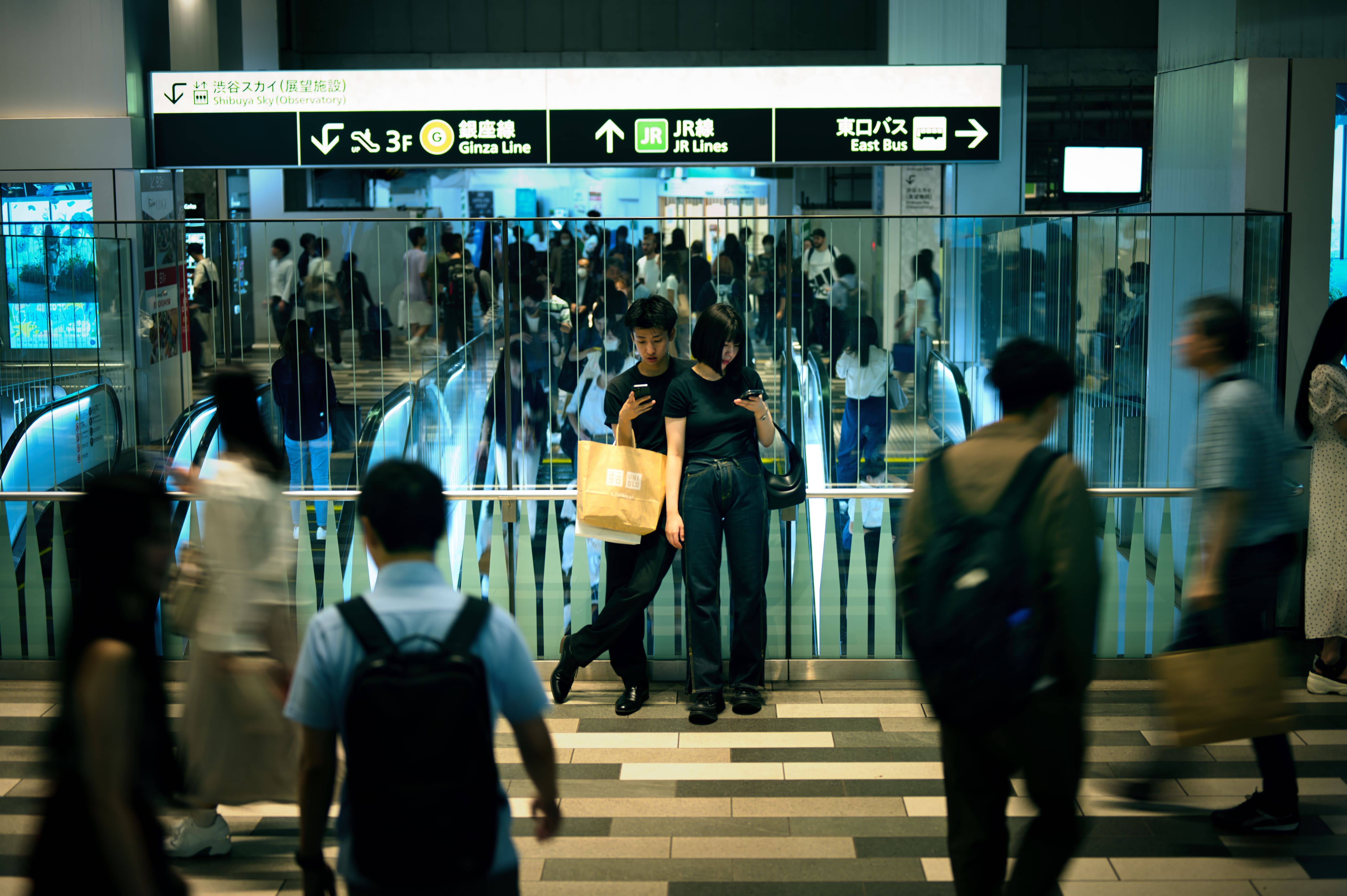 A traveller checking a smartphone rail app on a crowded Shinkansen platform in Japan during the Obon holiday rush
