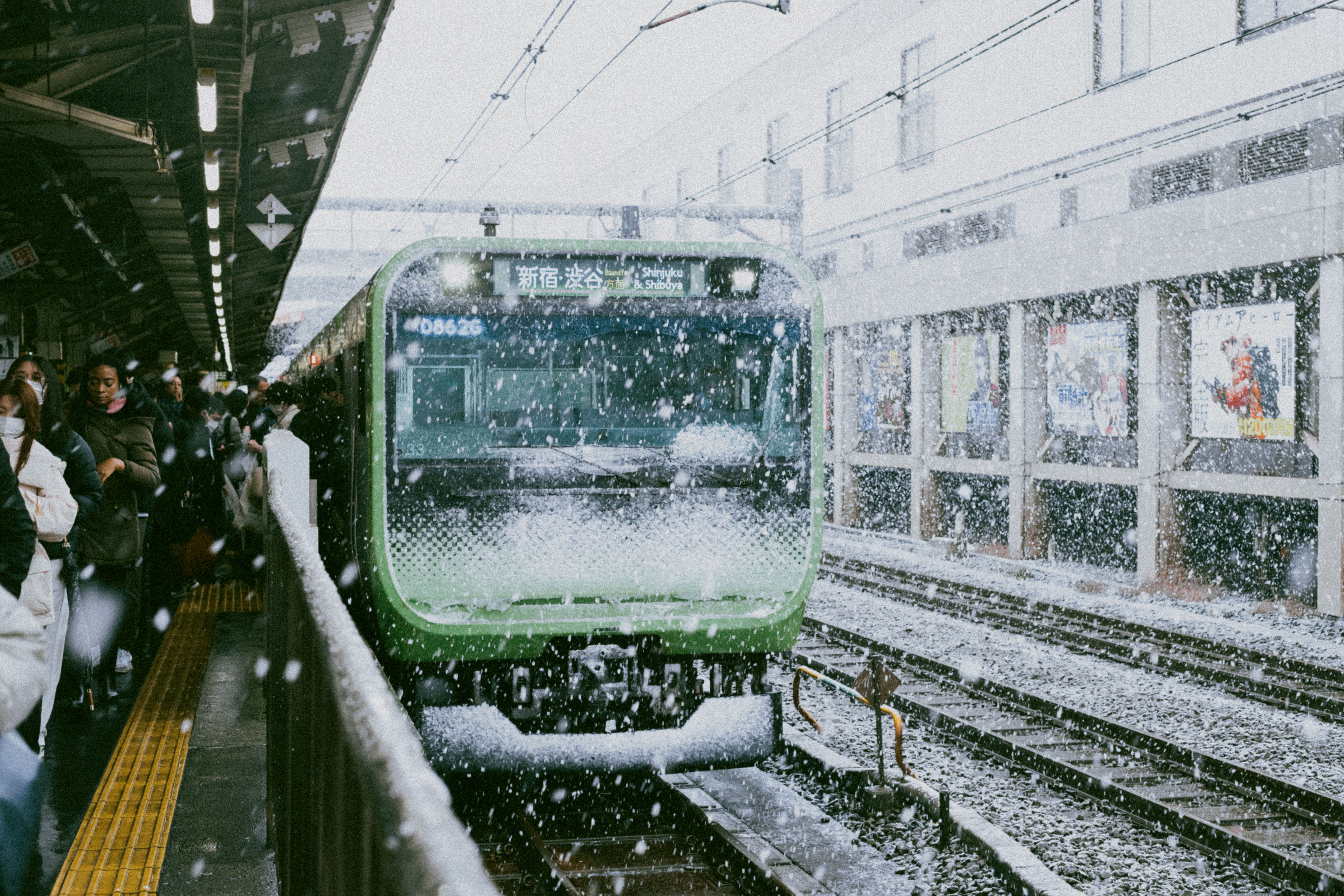The entrance of Odori subway station in central Sapporo in winter with snow piled on the pavement and the Sapporo TV Tower visible in the background