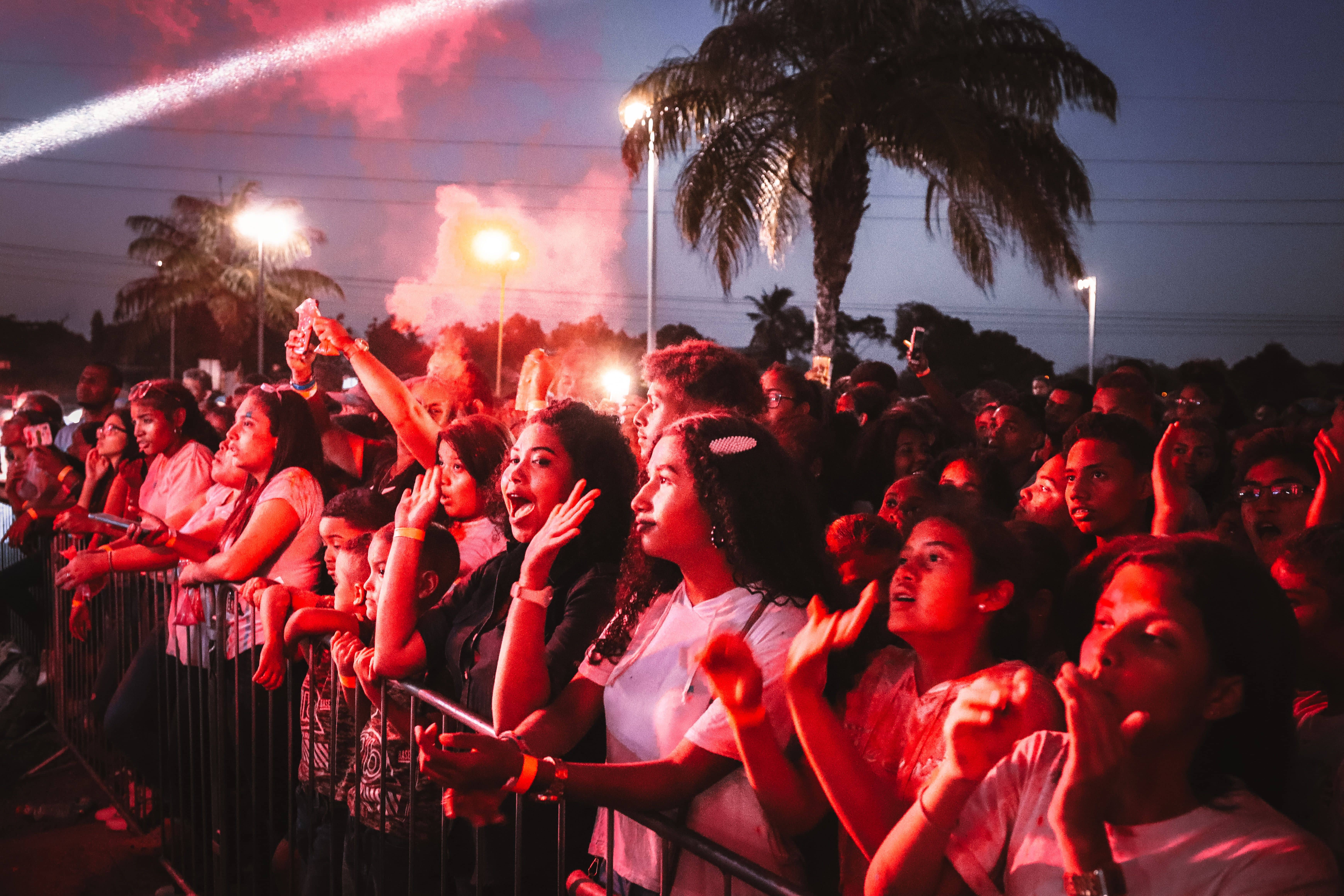 Festival-goers in light outfits and hats walking into EDC Orlando in late-afternoon sun at Tinker Field
