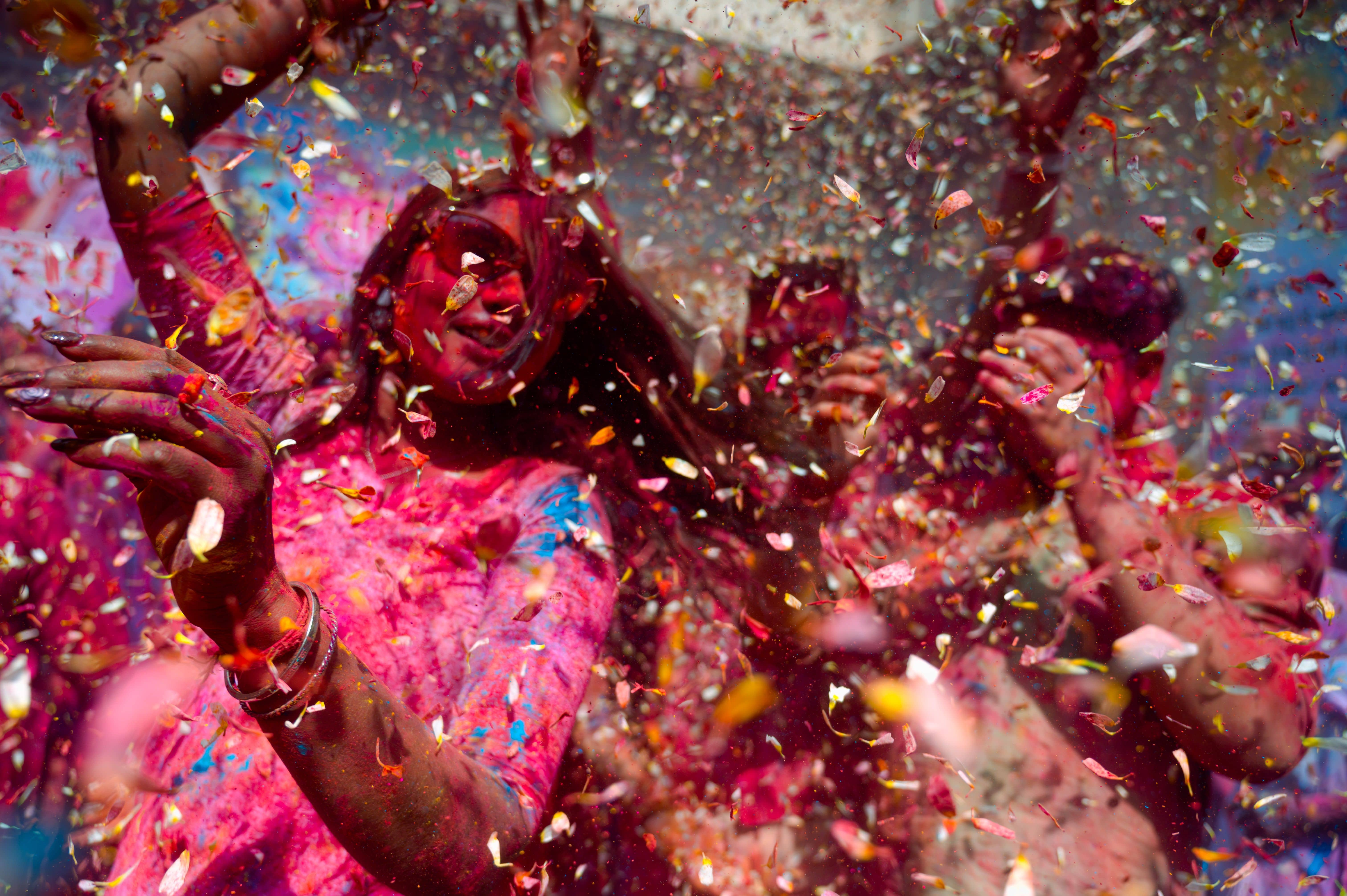 A DJ stage and a crowd covered in colour at an organised Holi party on a lawn in Delhi with rain-dance sprinklers