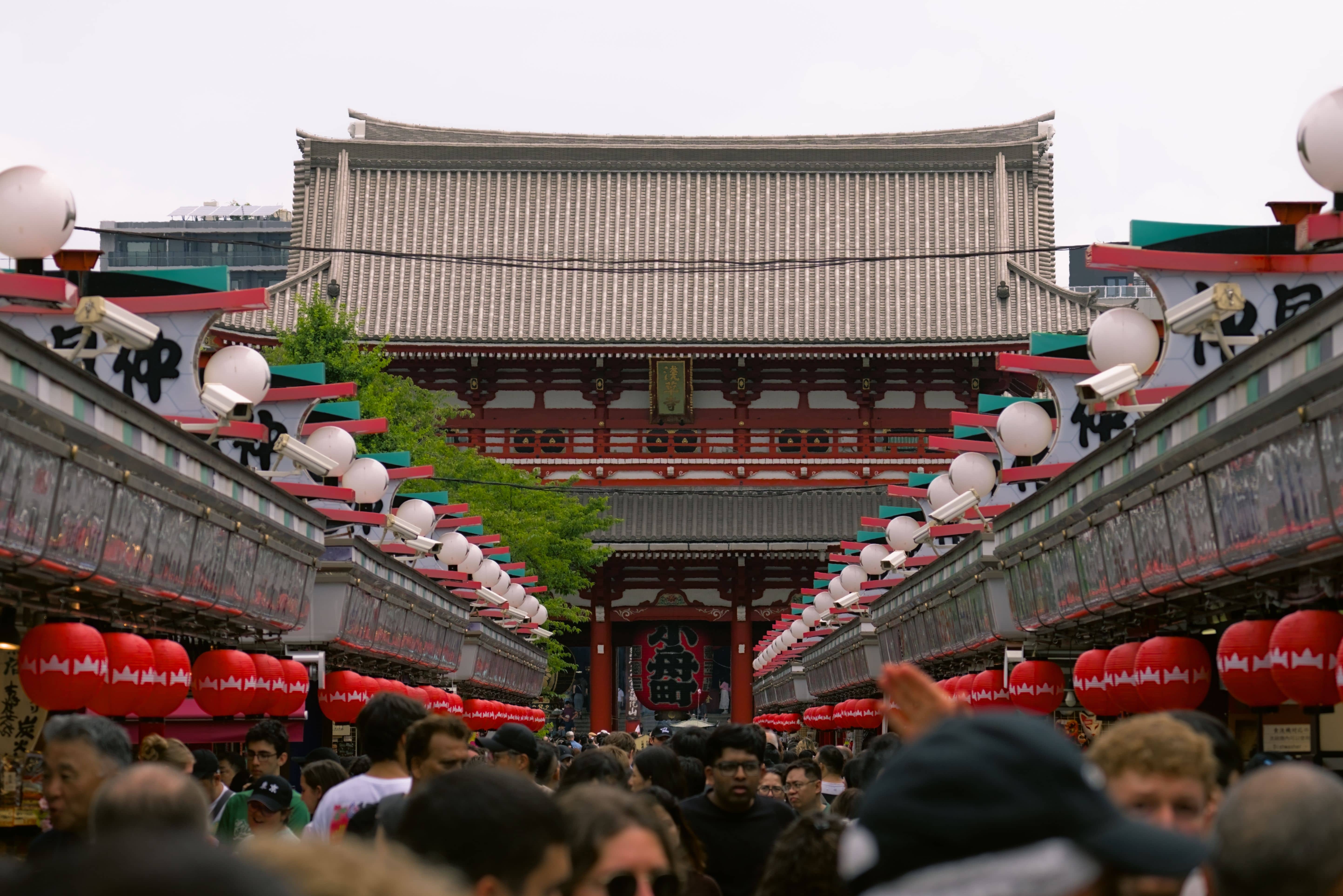 Spectators lining a narrow Asakusa shopping street as a neighbourhood mikoshi passes, with no barriers or ticket gates in sight