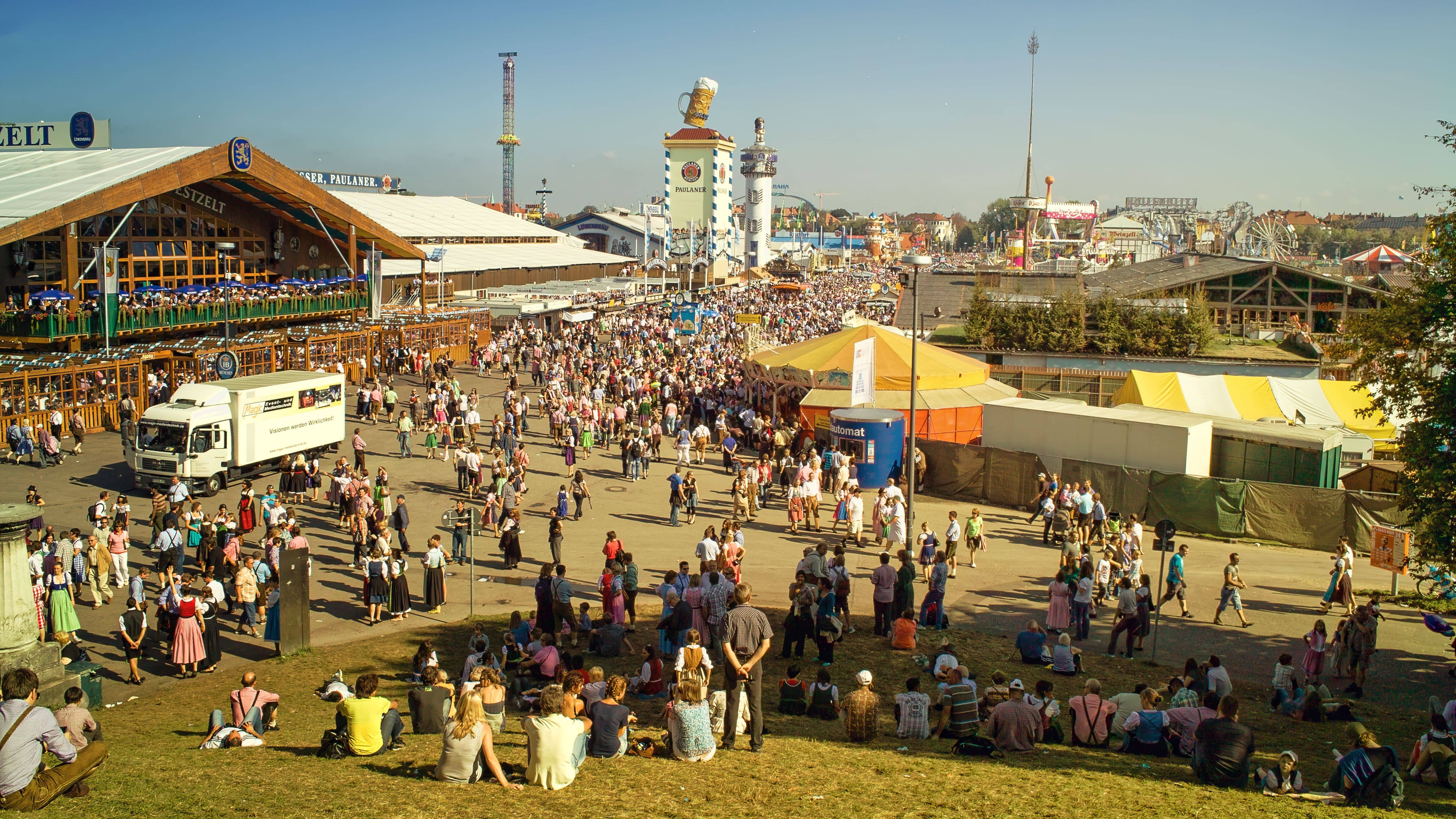 Crowds streaming out of Theresienwiese U-Bahn station towards the Oktoberfest entrance with the Bavaria statue and tents in the background