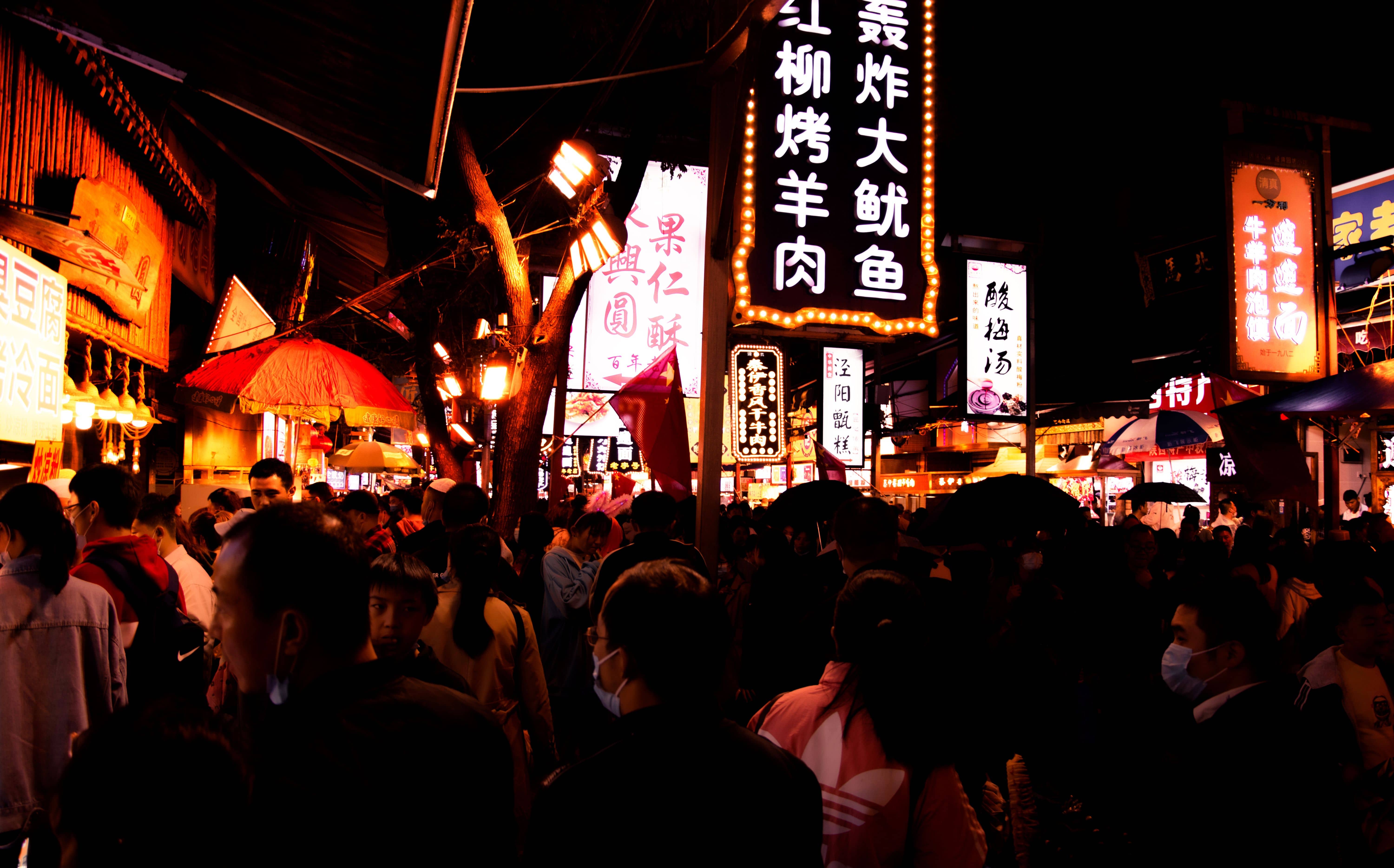 Visitors in winter coats and scarves walking under rows of red lanterns on a cold, clear evening in Shanghai's Old City