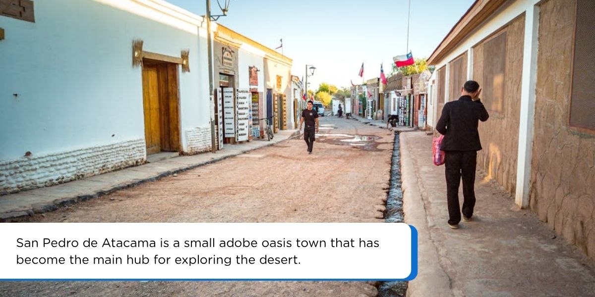 Adobe buildings and dusty streets of San Pedro de Atacama town with volcano in background