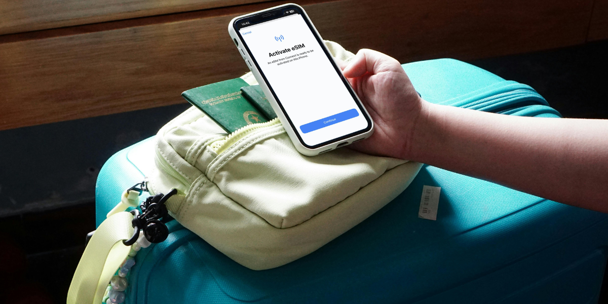 A person holding a phone showing “Activate eSIM” screen, placed on a travel backpack with a passport visible