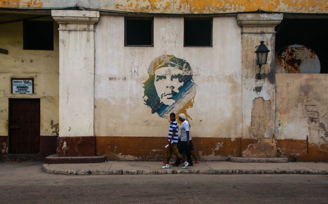 Two pedestrians walking past a mural on a weathered wall in Cartagena Colombia