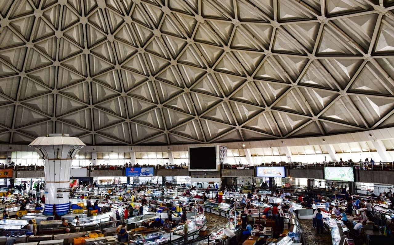 Chorsu Bazaar in Tashkent with vendors selling fruits, bread, and spices under a blue dome