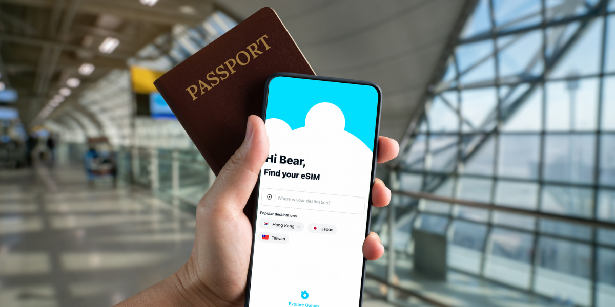 Traveler holding passport and phone showing GoHub eSIM setup screen at the airport