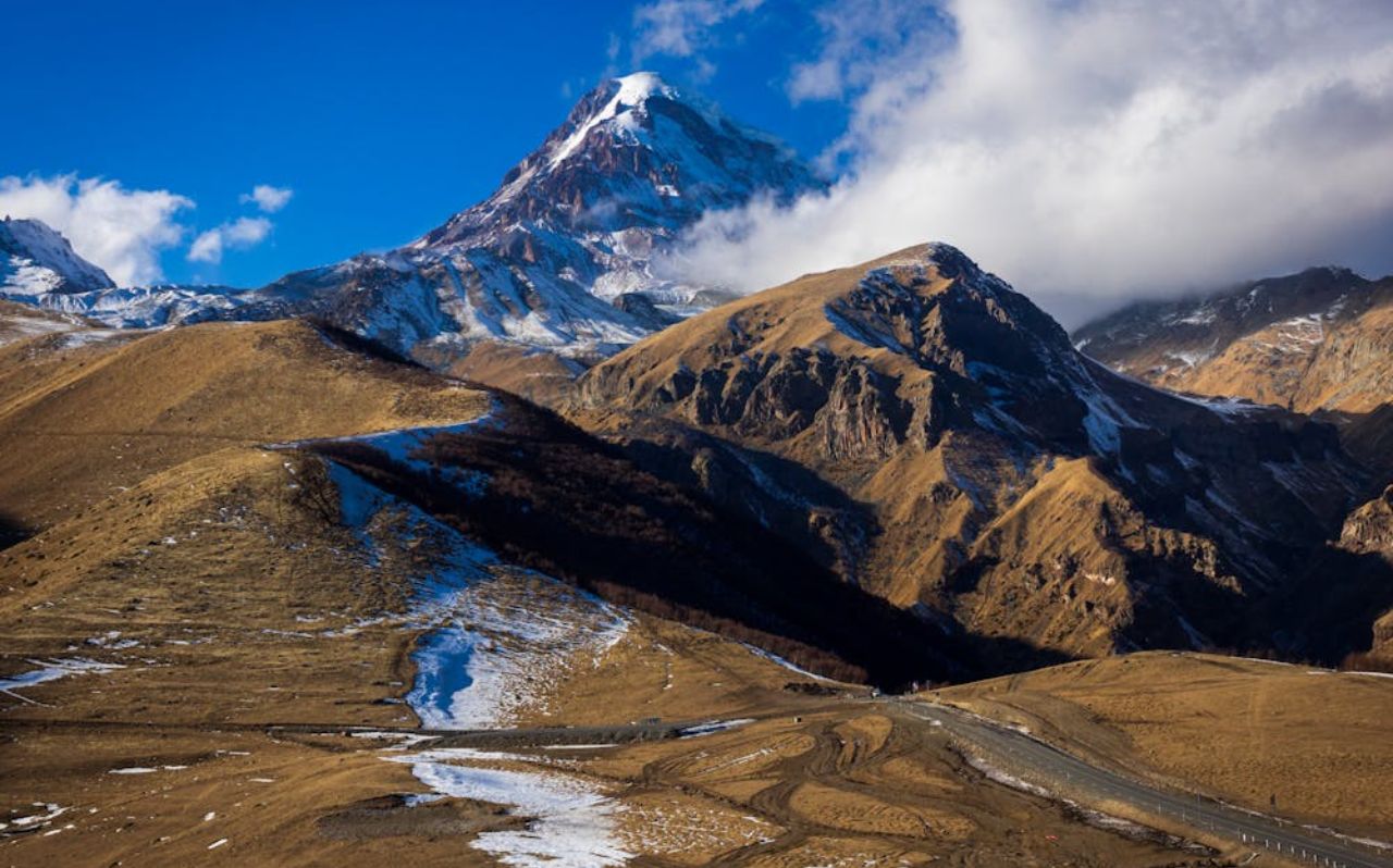 Mountain road leading to Kazbegi with snow-capped peaks in northern Georgia