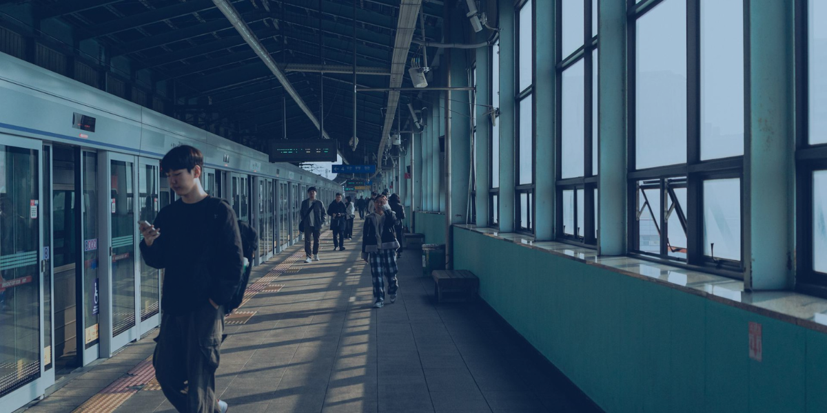 Commuters walking along a subway platform in a Korean train station