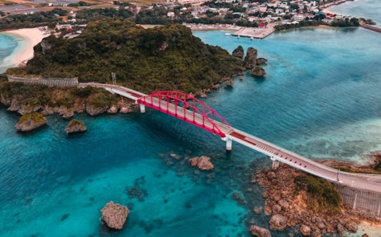 Red bridge crossing turquoise water along Okinawa coastline