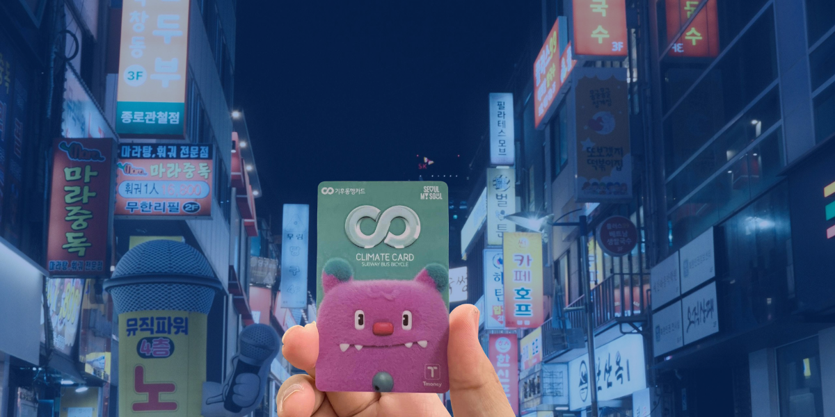 Hand holding Seoul Climate Card in front of Korean night street