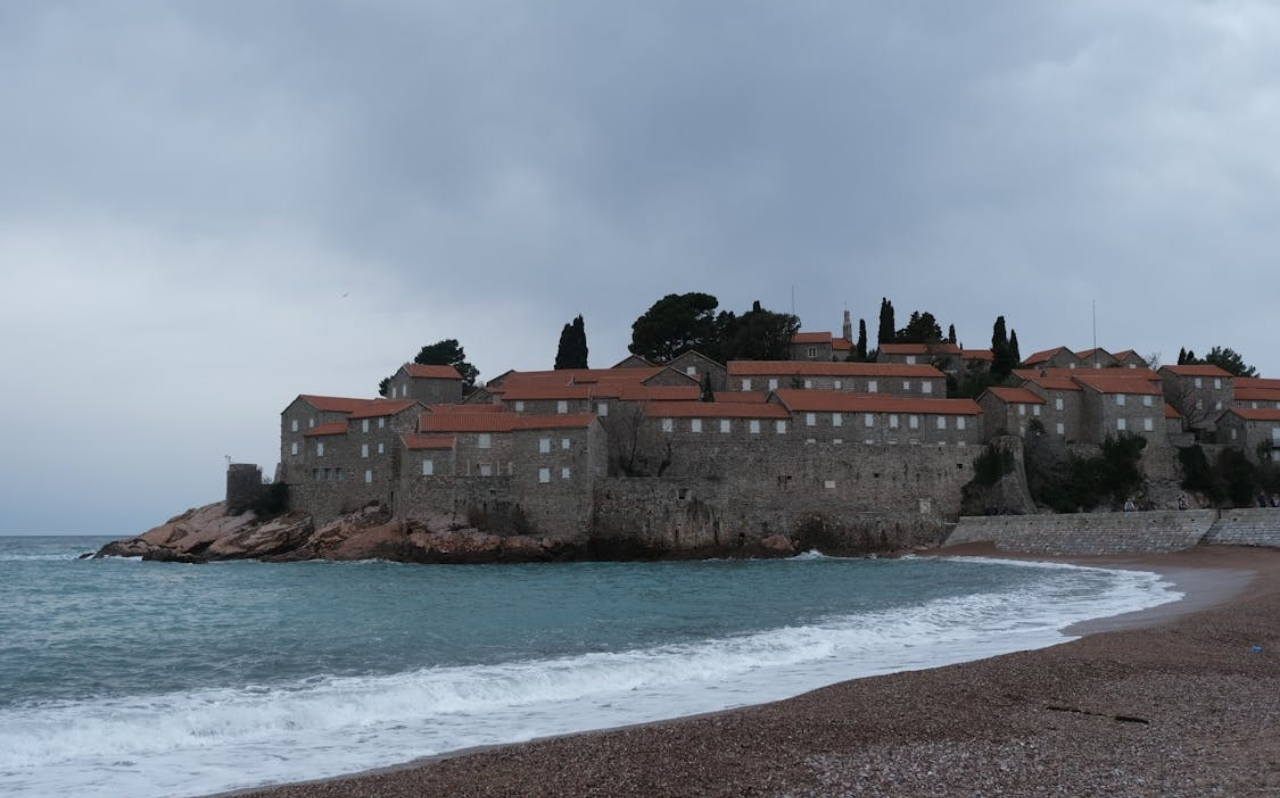 Pebble beach near Sveti Stefan with deep blue water and steep coastal terrain