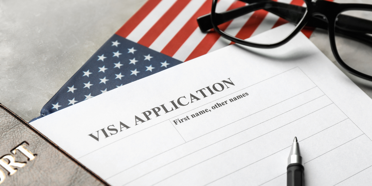 Form đăng ký visa Mỹ năm 2025 đặt trên hộ chiếu và cờ Mỹ – biểu tượng cho hồ sơ xin visa thăm thân